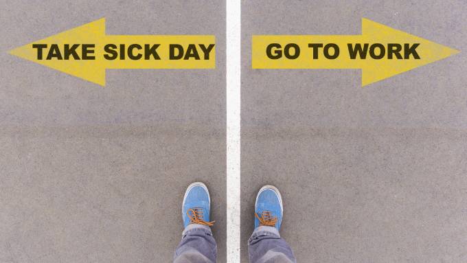 A vertical white line divides a pair of feet. One foot is near a yellow arrow saying, “Take a sick day,” and the other, “Go to work.”