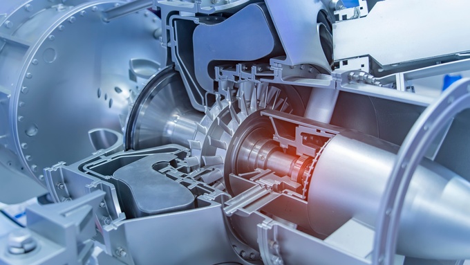 A close-up of a complex 3D-printed turbine engine model, made from metal and plastic in a warehouse factory.