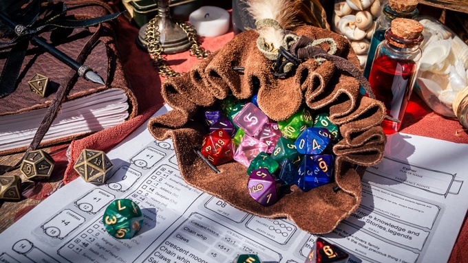 On a small table, there's a leather dice bag with multiple dice rolling out on top of a tabletop game character sheet.