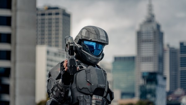 A cosplayer in a gray-and-black UNSC armor costume. The design is from the Halo video game franchise.