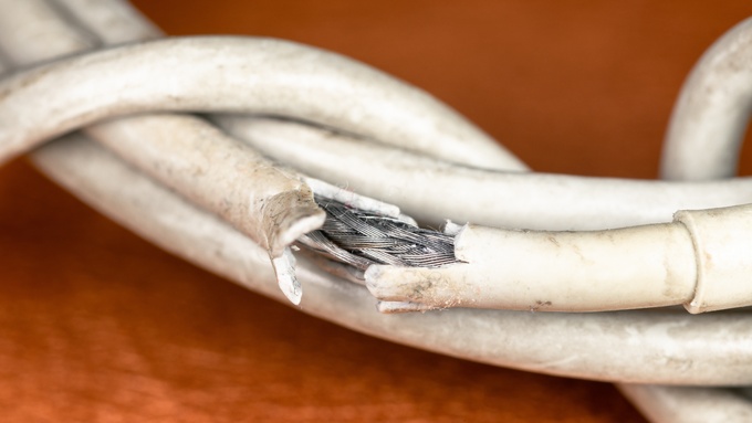 A close-up view shows a rolled-up white cable that is fraying. The cable is dirty and is exposing the inner wires.